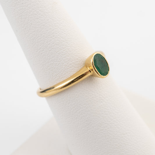 18ct gold emerald solitaire ring shown on a ring stand