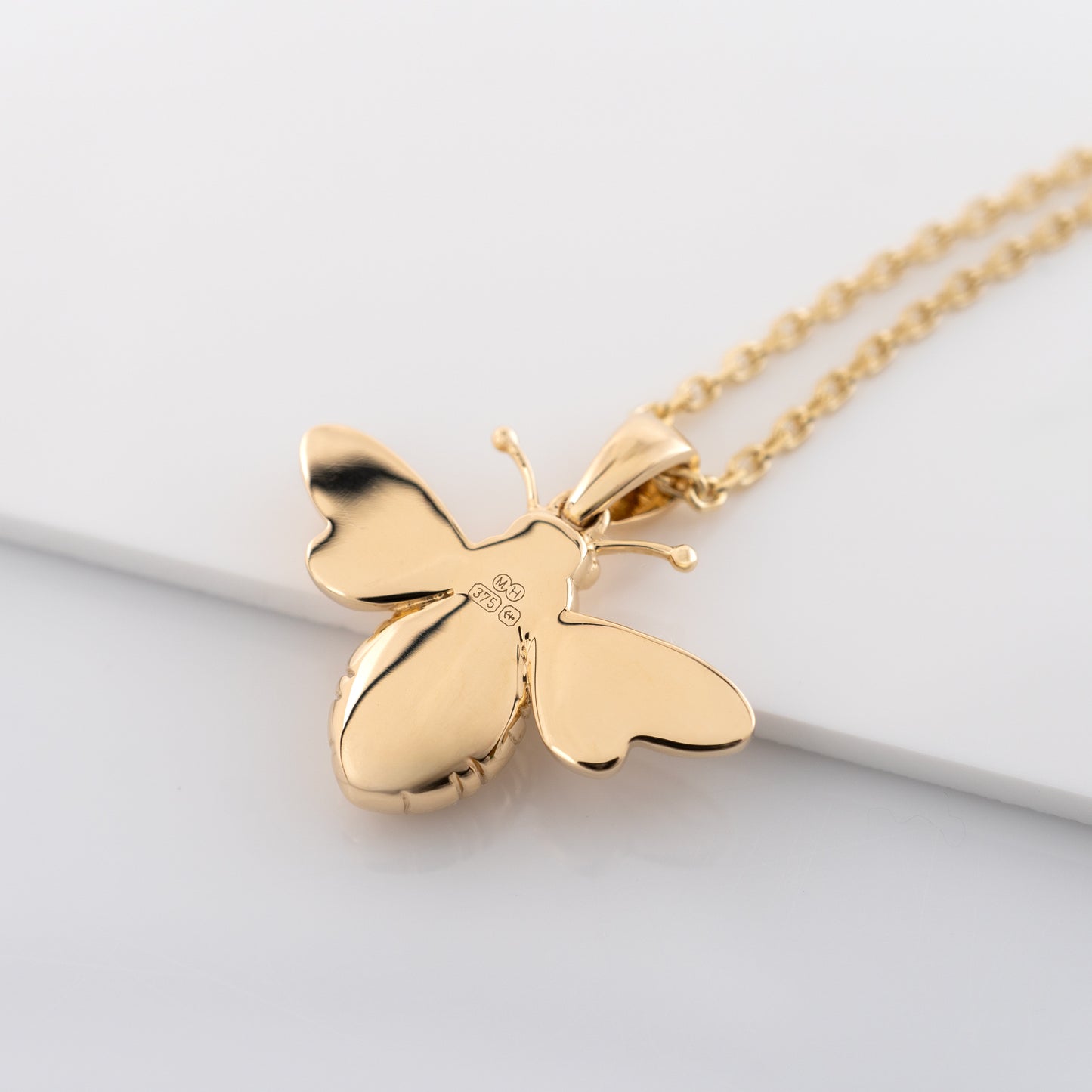9ct gold bee pendant necklace showing the smooth reverse side with full UK Assay Hallmarks and sponsor mark MH