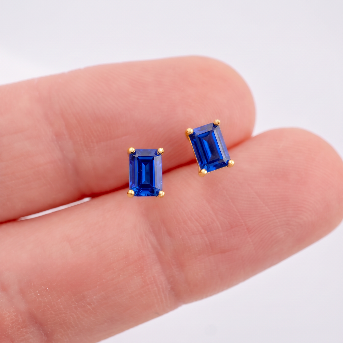 6 x 4mm lab sapphire rectangle stud earrings shown on the hand