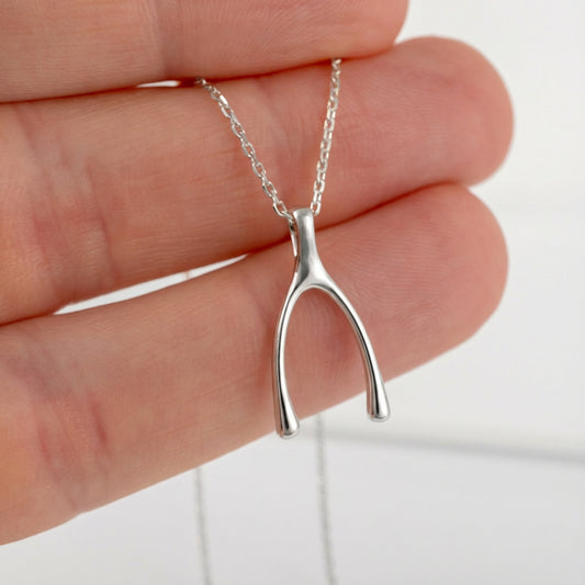 sterling silver wishbone necklace in hand showing scale
