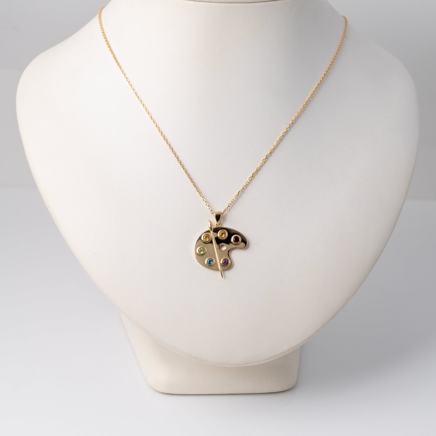 Gold artist palette pendant on bust display to show scale