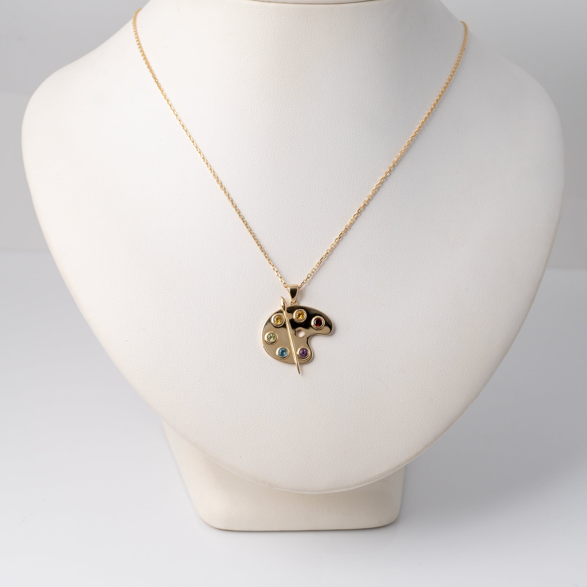 Gold artist palette pendant on bust display to show scale