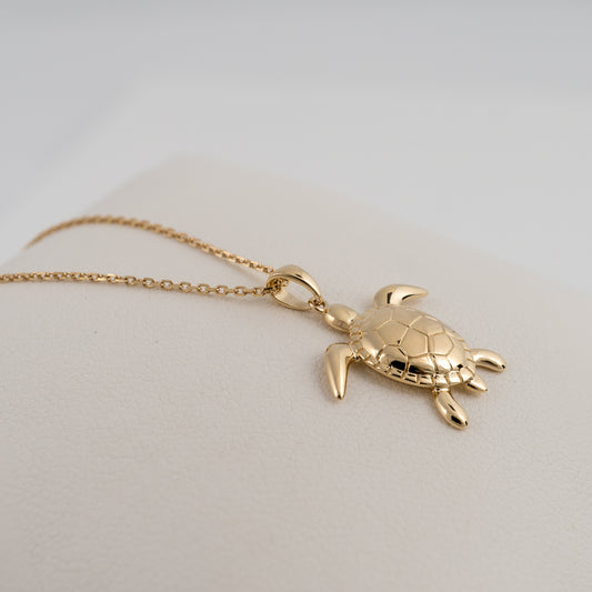 gold-sea-turtle-necklace-fdraped on a cushion showing side and depth