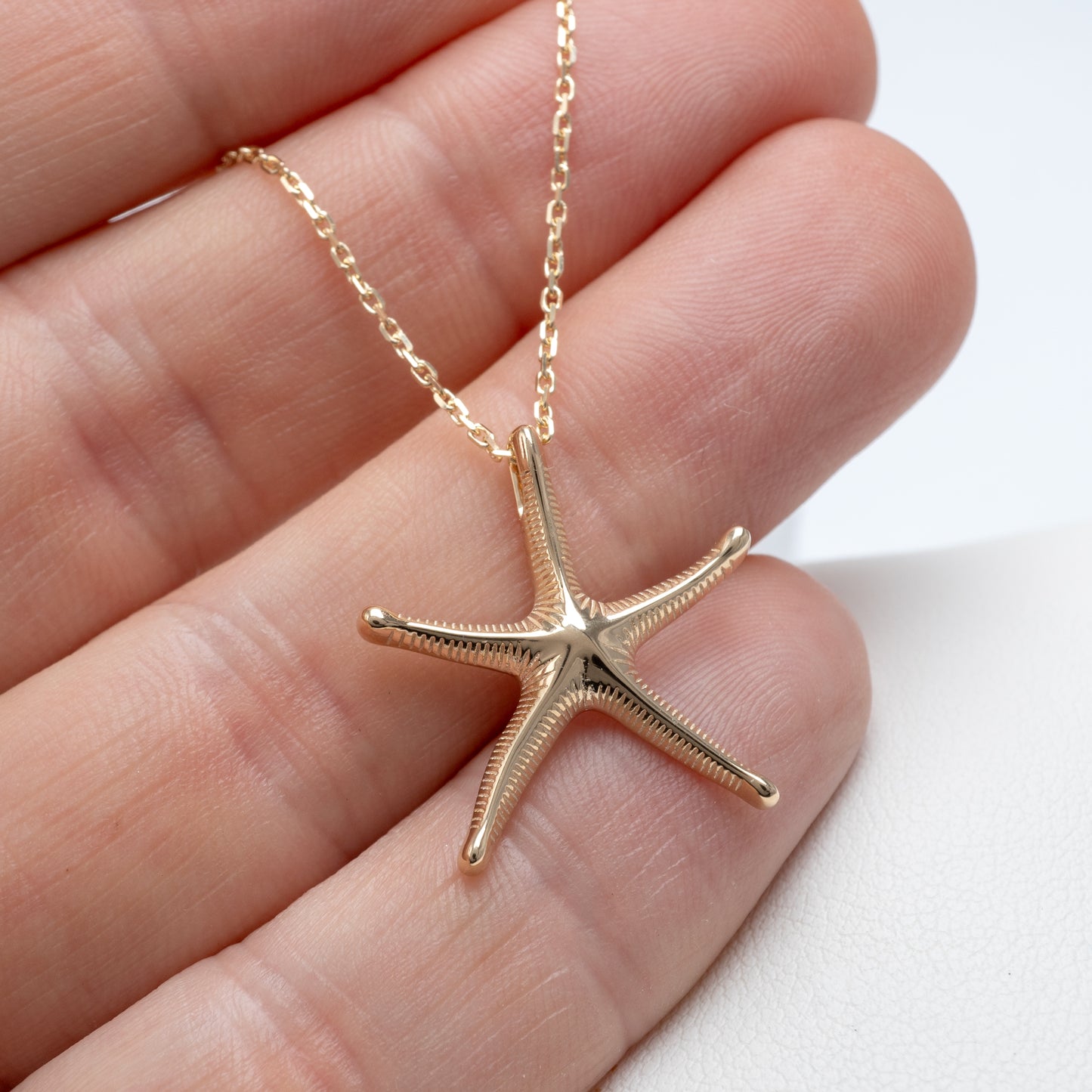 gold starfish necklace in hand