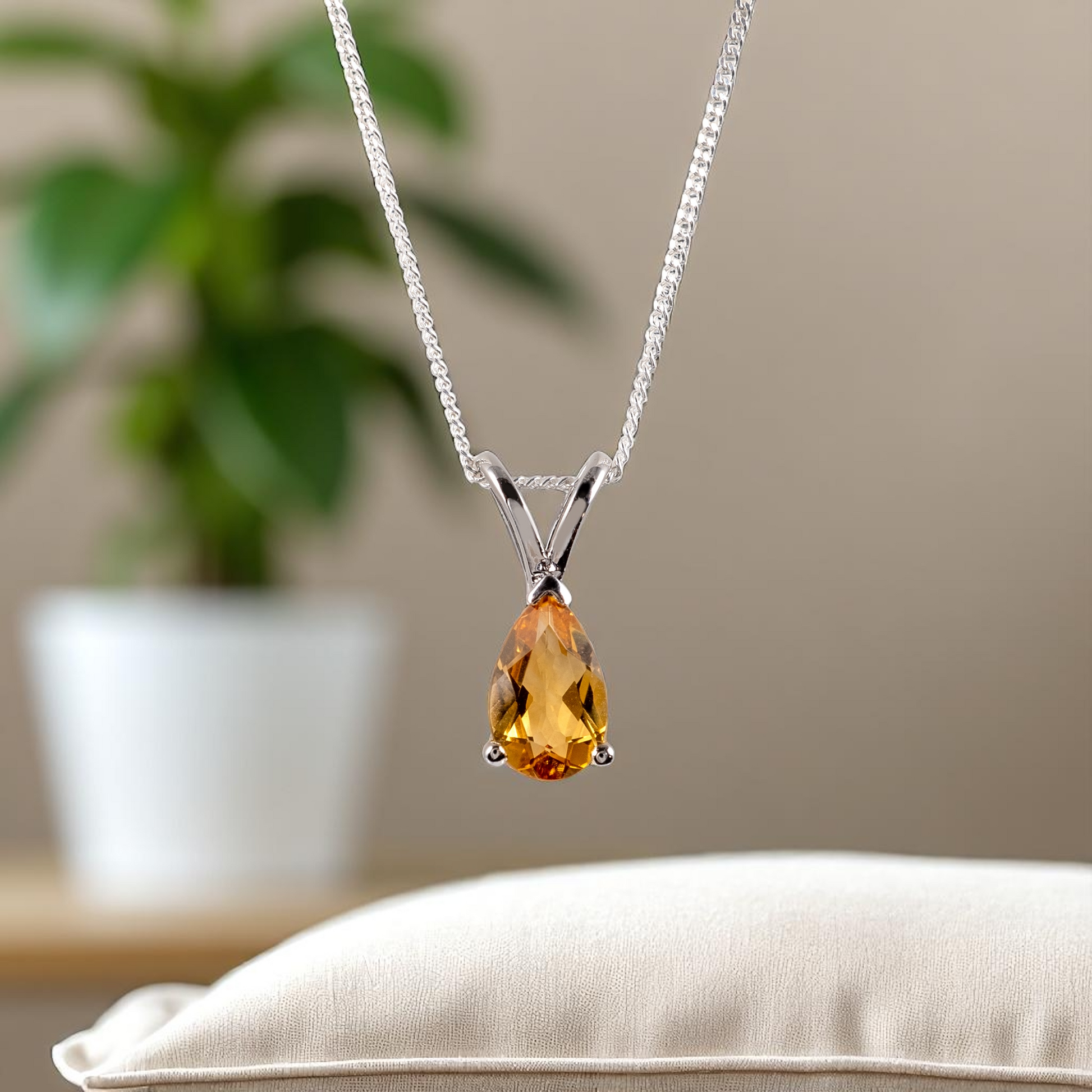 citrine teardrop necklace with green plant in background