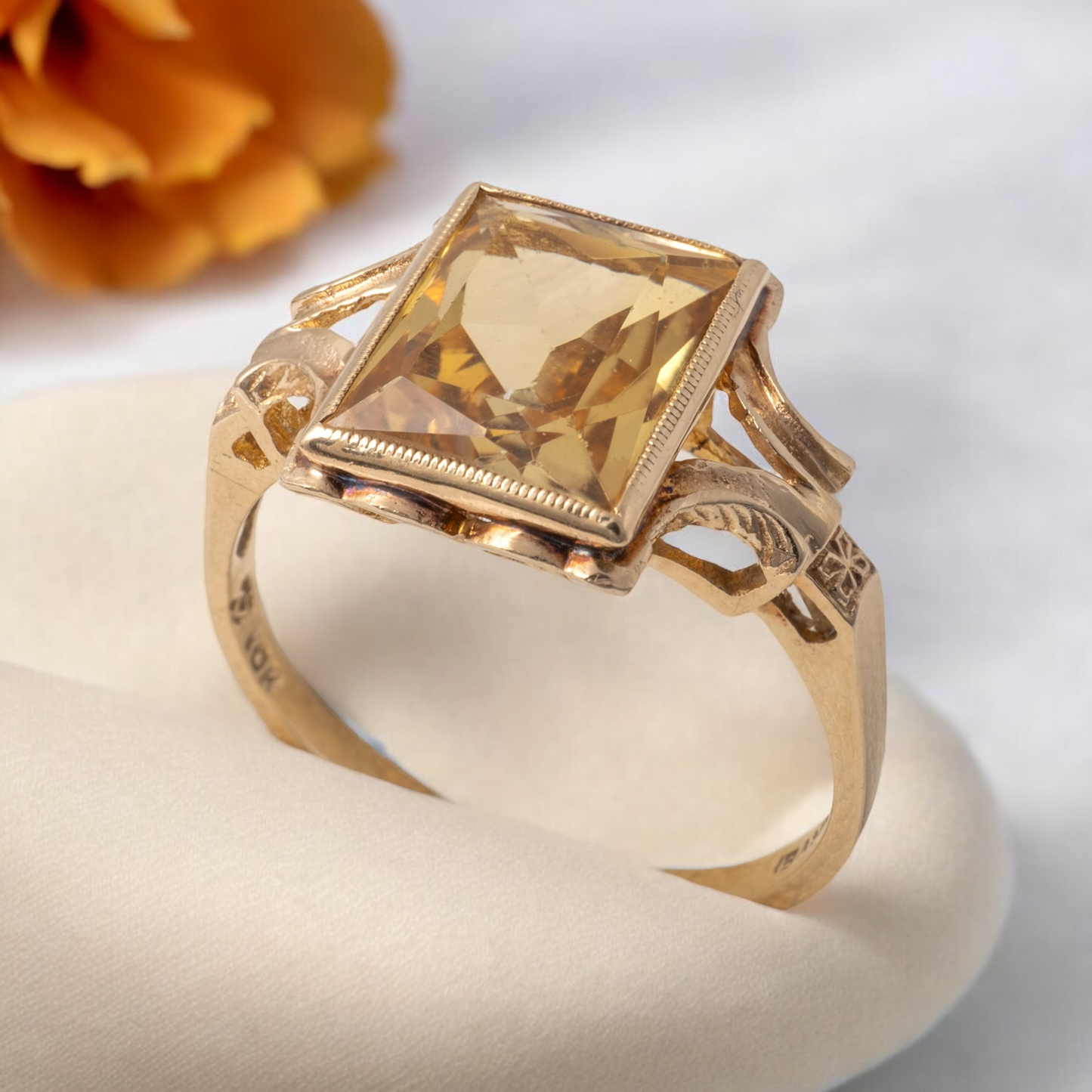 Elegant vintage citrine ring with rectangular gemstone and 9ct gold bifurcated shoulders, styled with floral decor in the background