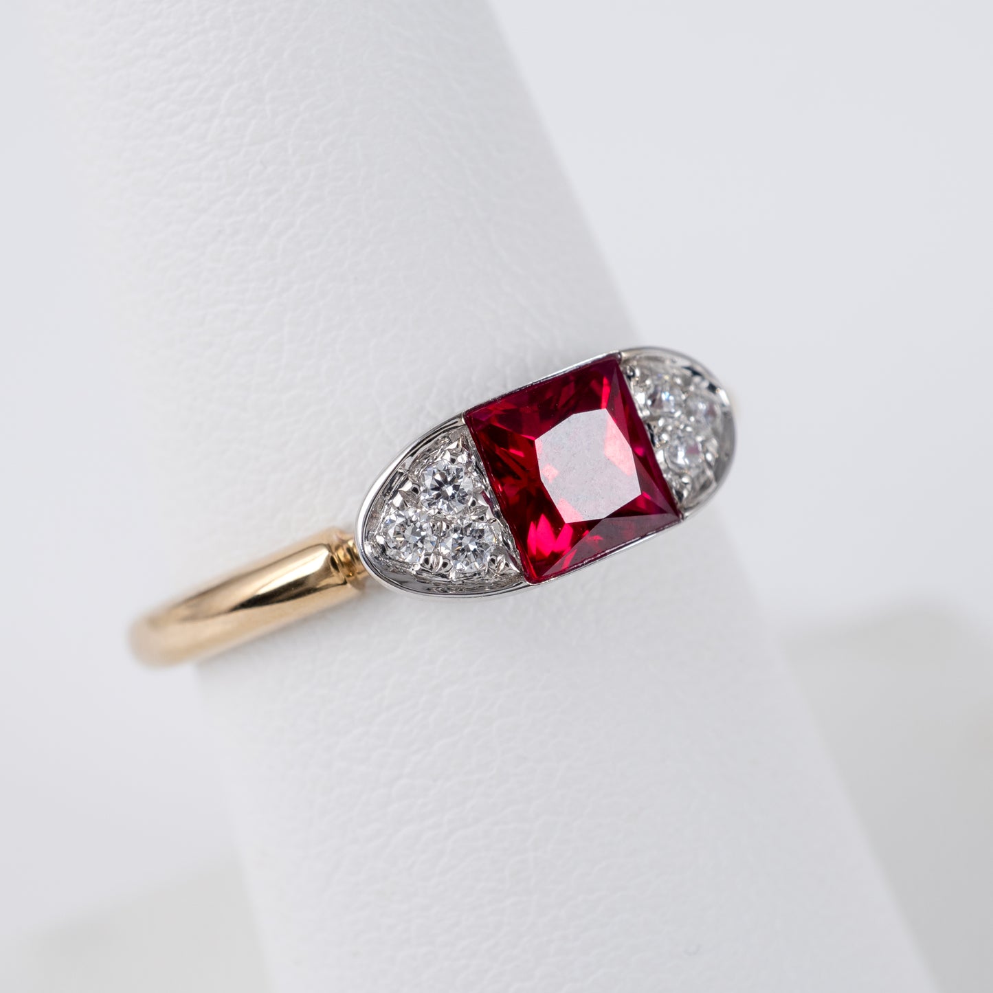 Contemporary ruby ring displayed on stand, featuring radiant-cut lab ruby and diamond accents in 9ct gold by Hunters Fine Jewellery.