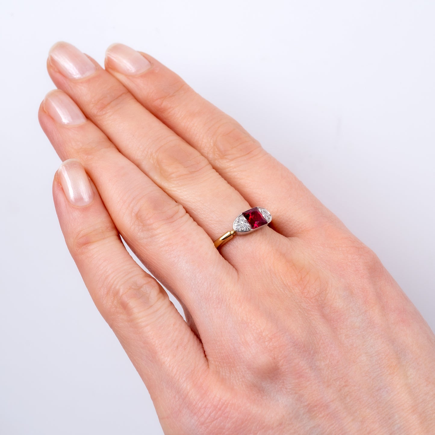 Contemporary ruby ring worn on hand, featuring 9ct gold band with radiant-cut lab ruby and diamond accents by Hunters Fine Jewellery.