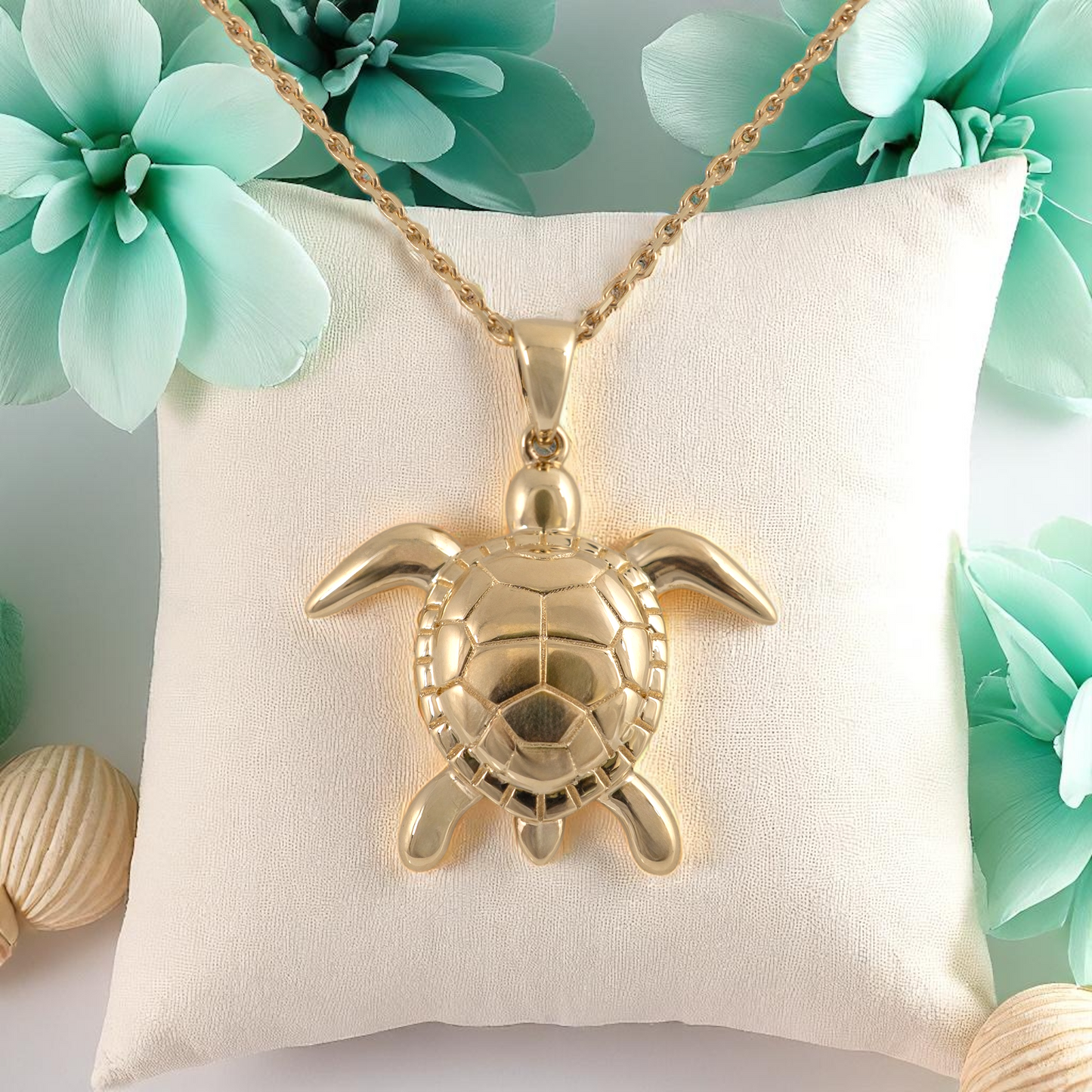 9ct gold sea turtle necklace styled on cushion with ocean-themed background