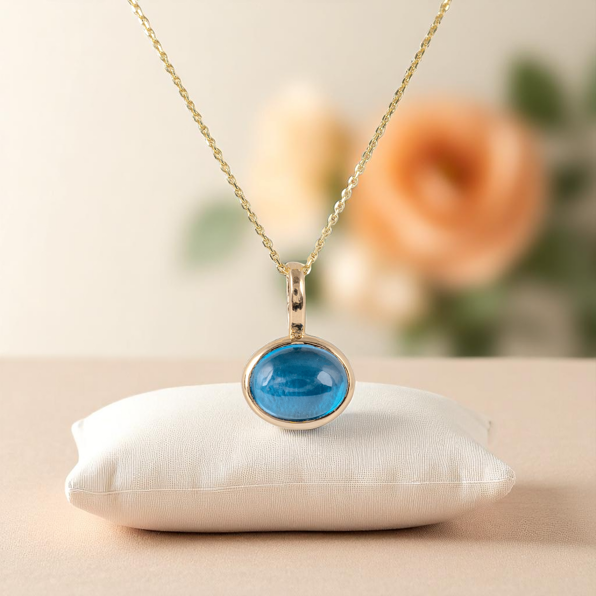 london blue topaz pendant with subtle peach flower in the background