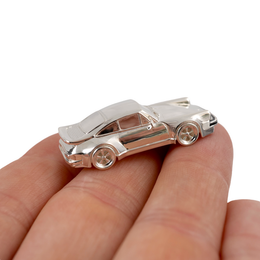 Small sterling silver Porsche 911 model held in hand showing fine craftsmanship and detail