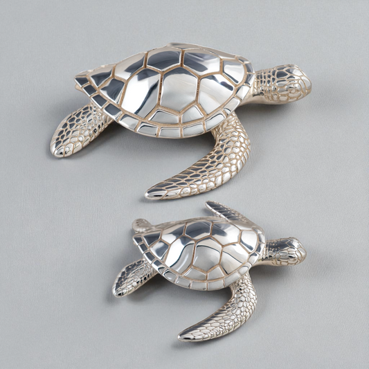 Two silver turtle figurines on a gray background