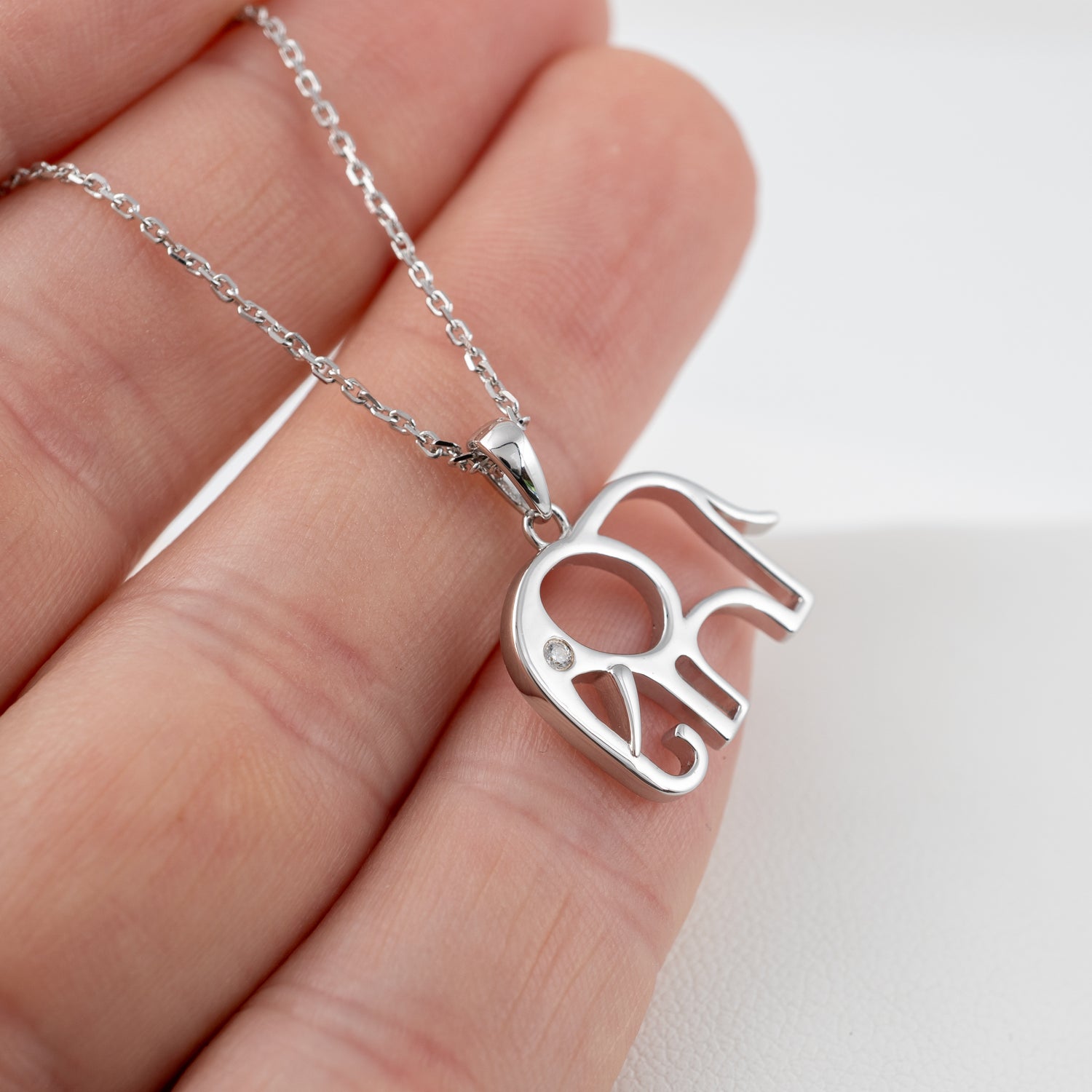 Small sterling silver elephant necklace pendant shown in hand