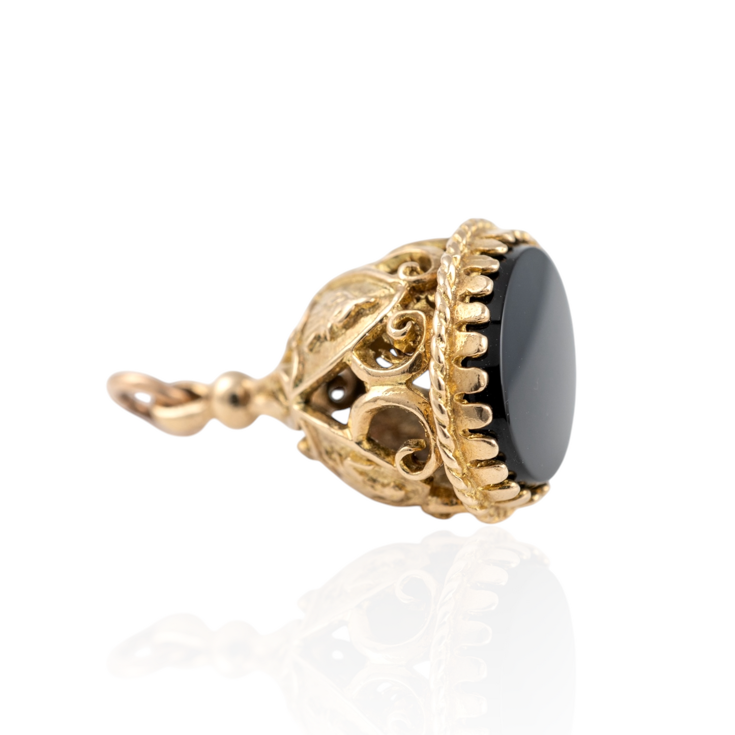 Vintage 9ct gold fob pendant with heraldic motifs and a smooth black onyx base, featuring intricate openwork scroll details