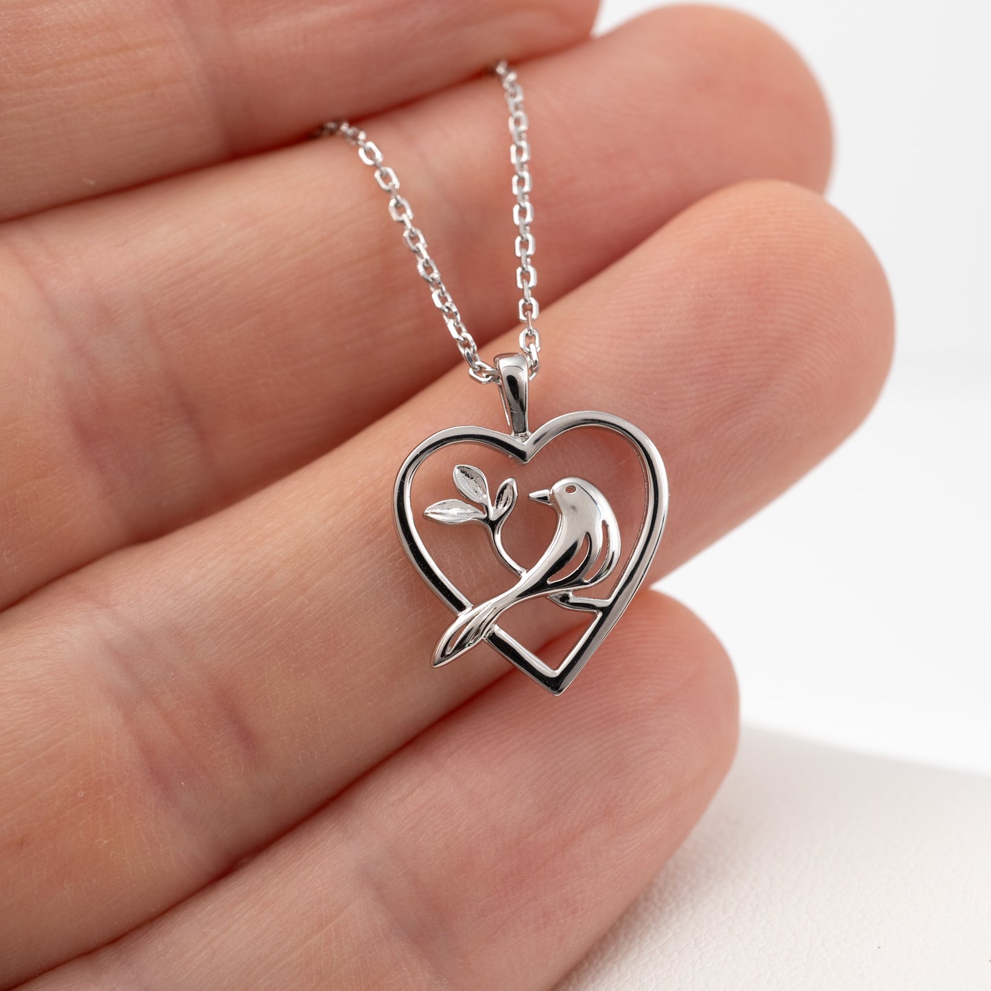 Sterling silver bird pendant necklace held in hand for scale