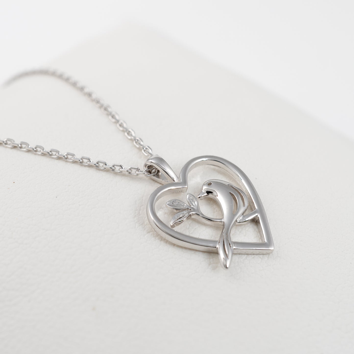 Side view of sterling silver bird necklace with heart-shaped pendant