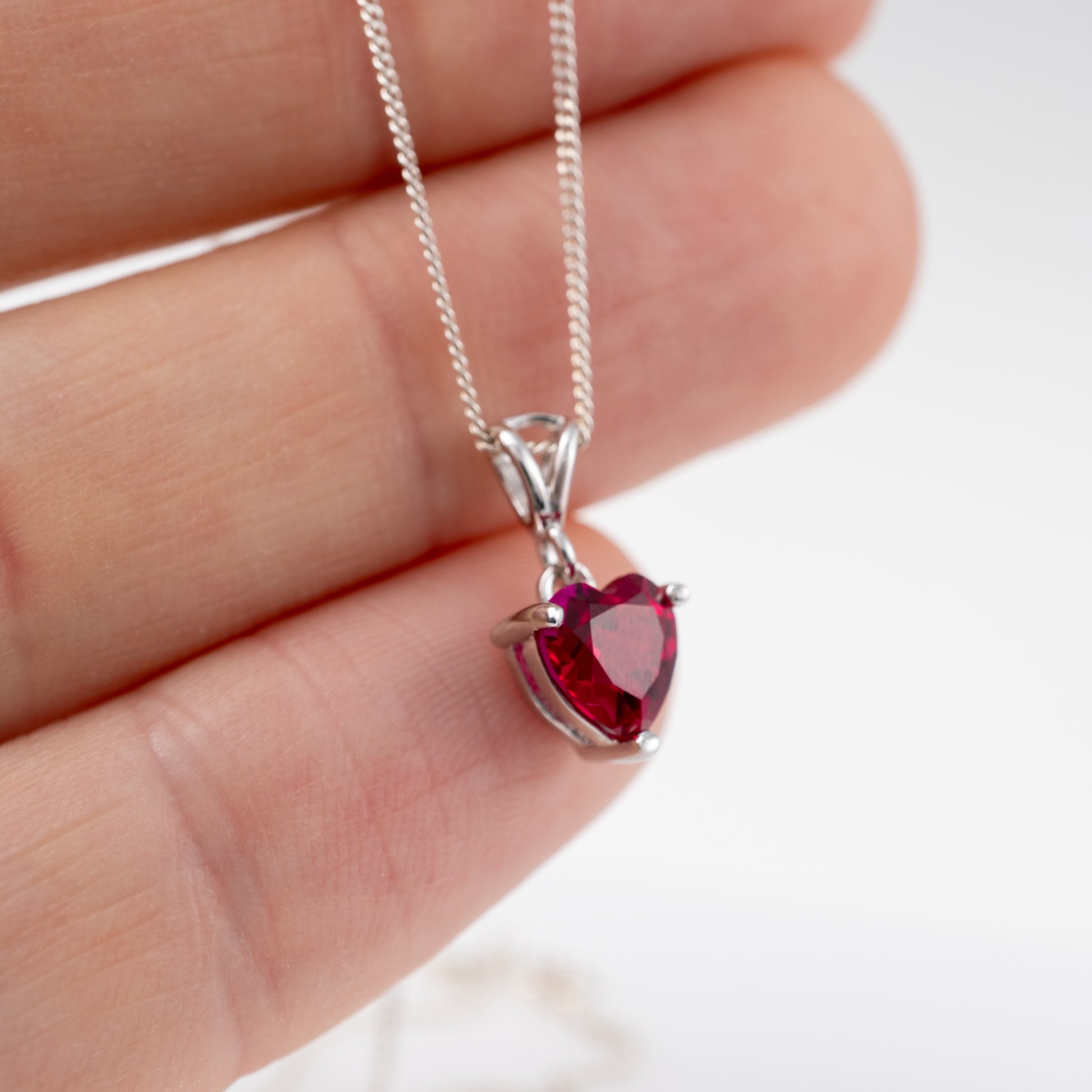 close up side of lab ruby heart necklace silver bail and chain