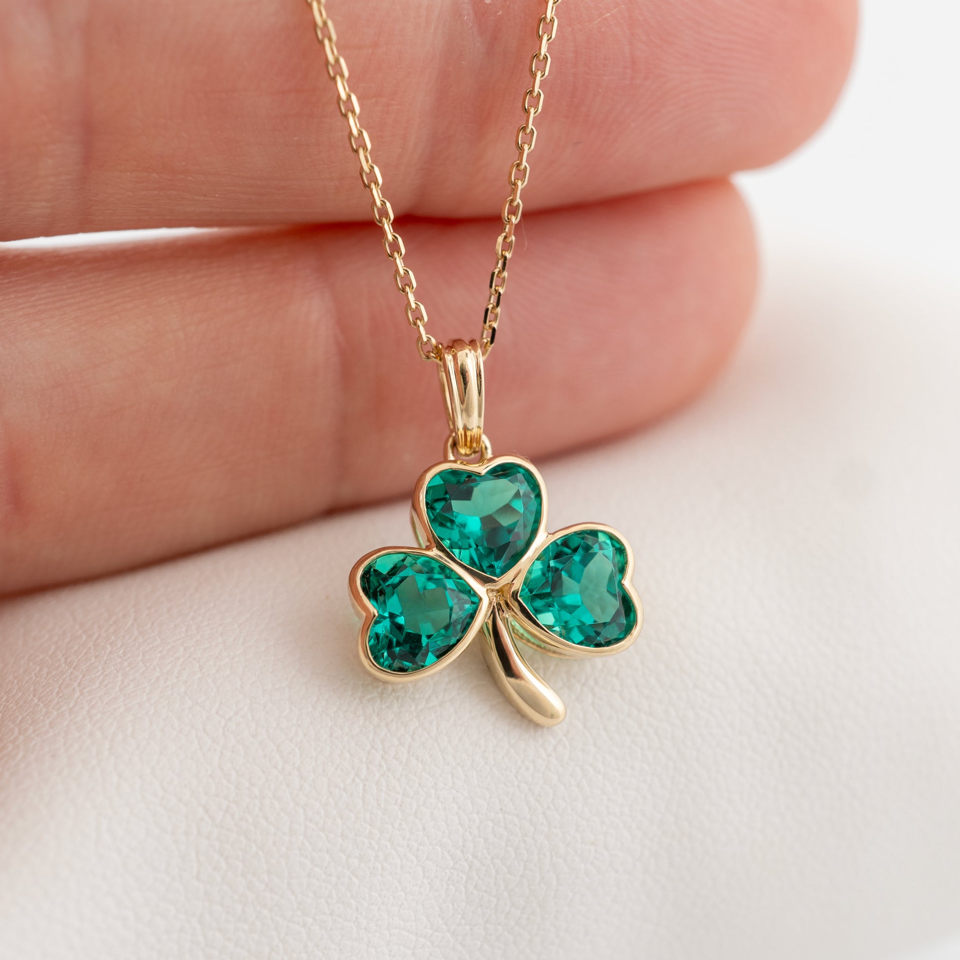 shamrock pendant with lab emeralds, shown worn by hand