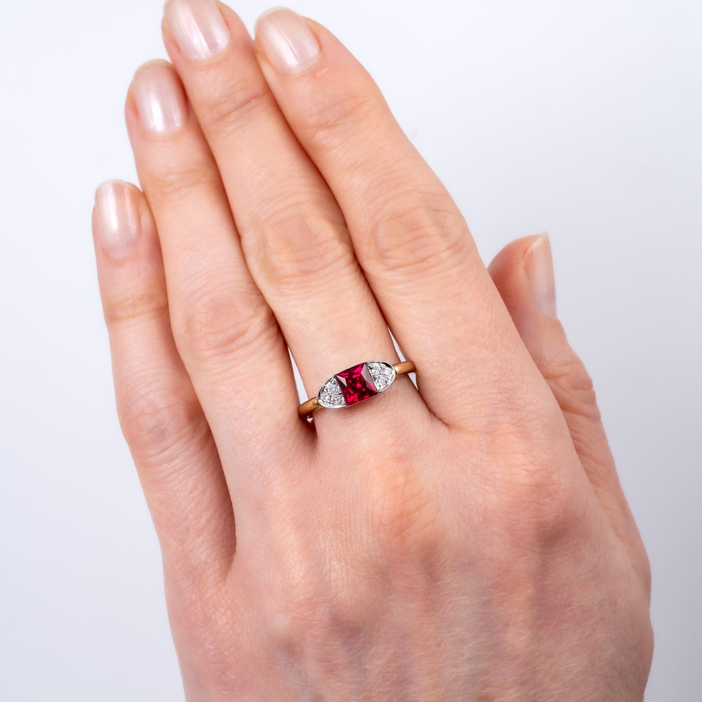Contemporary ruby ring worn on hand, featuring 9ct gold band with square-cut lab ruby and diamonds in boat design by Hunters Fine Jewellery.