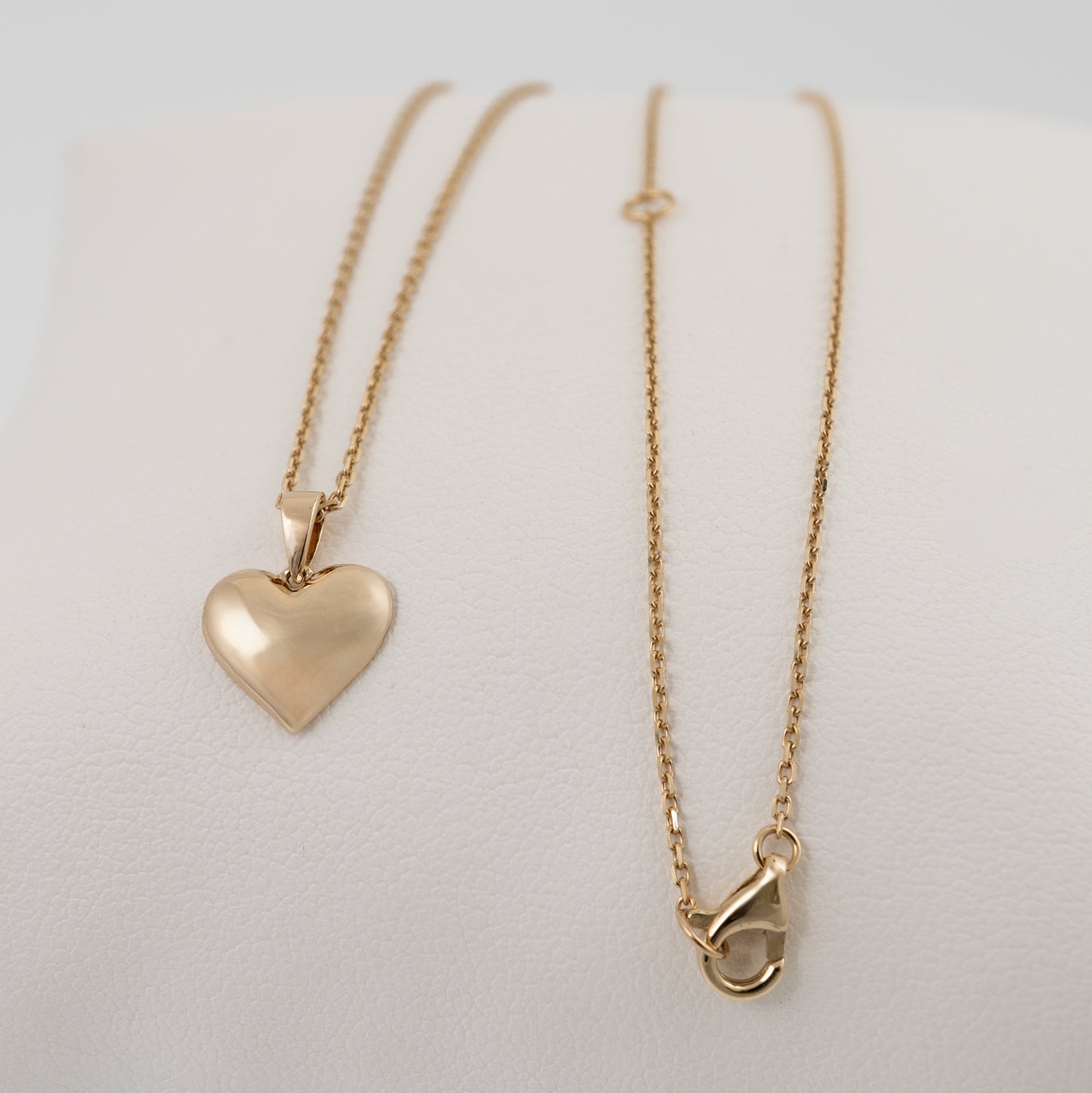 Dainty gold heart necklace with adjustable chain laid flat