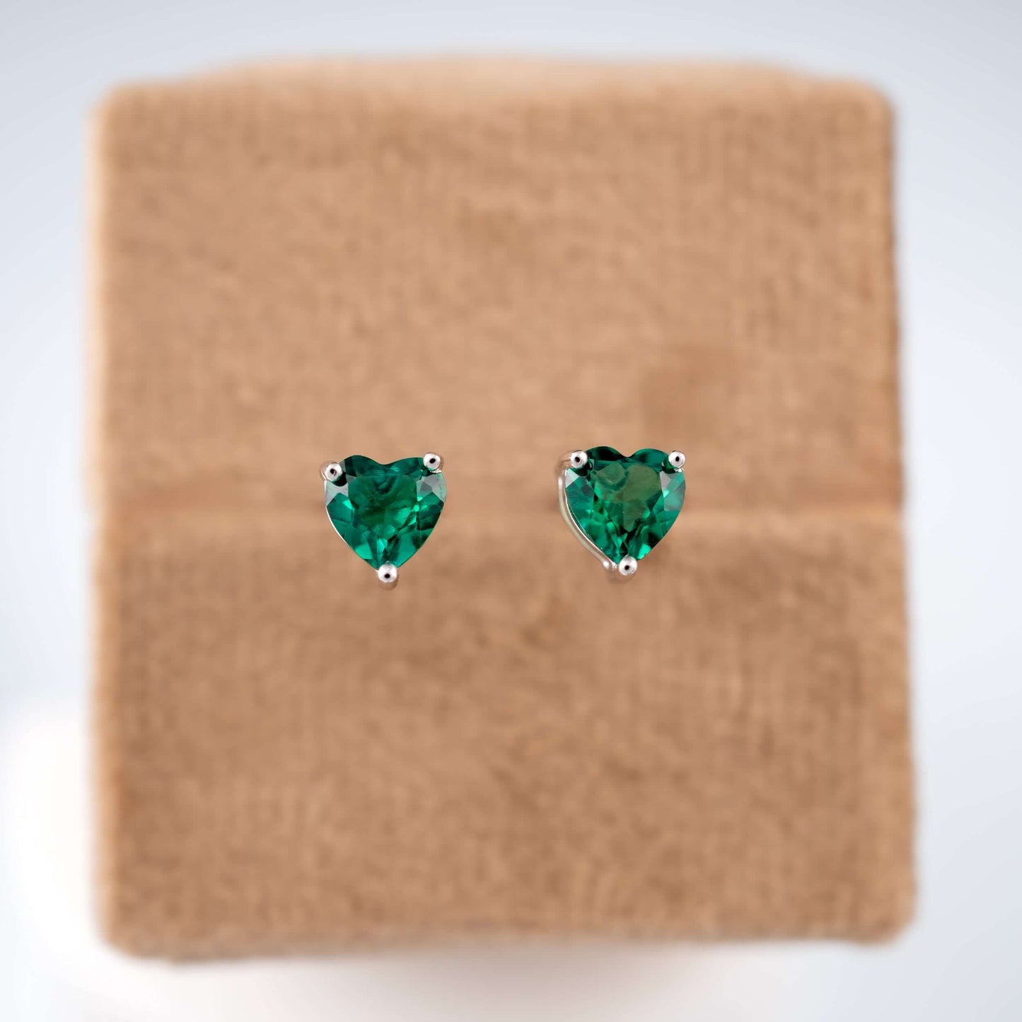 Sterling silver emerald heart studs on brown base