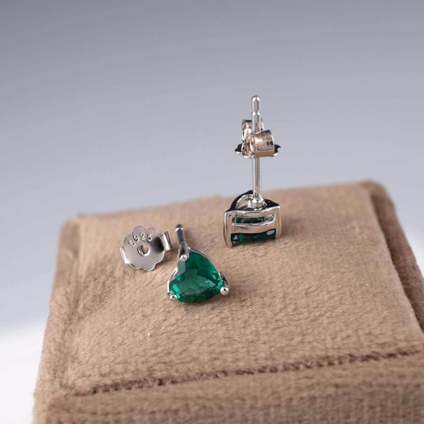 Side view of emerald heart stud earrings and backs