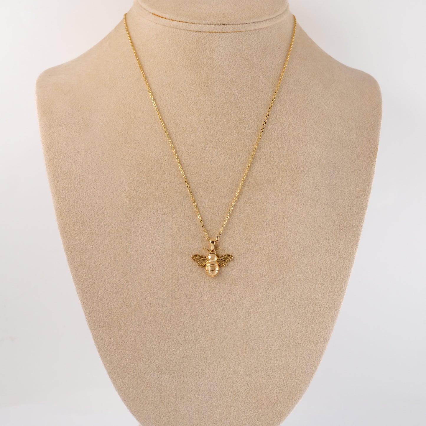 Gold bee pendant necklace displayed on a bust, demonstrating its size and how it sits when worn.