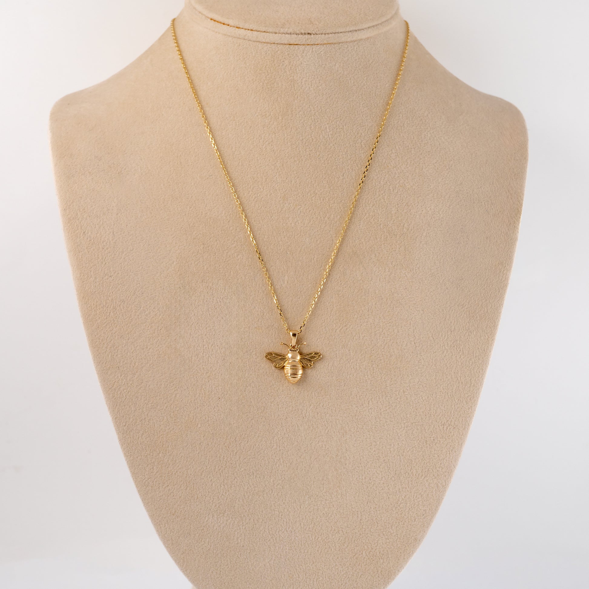 Gold bee pendant necklace displayed on a bust, demonstrating its size and how it sits when worn.