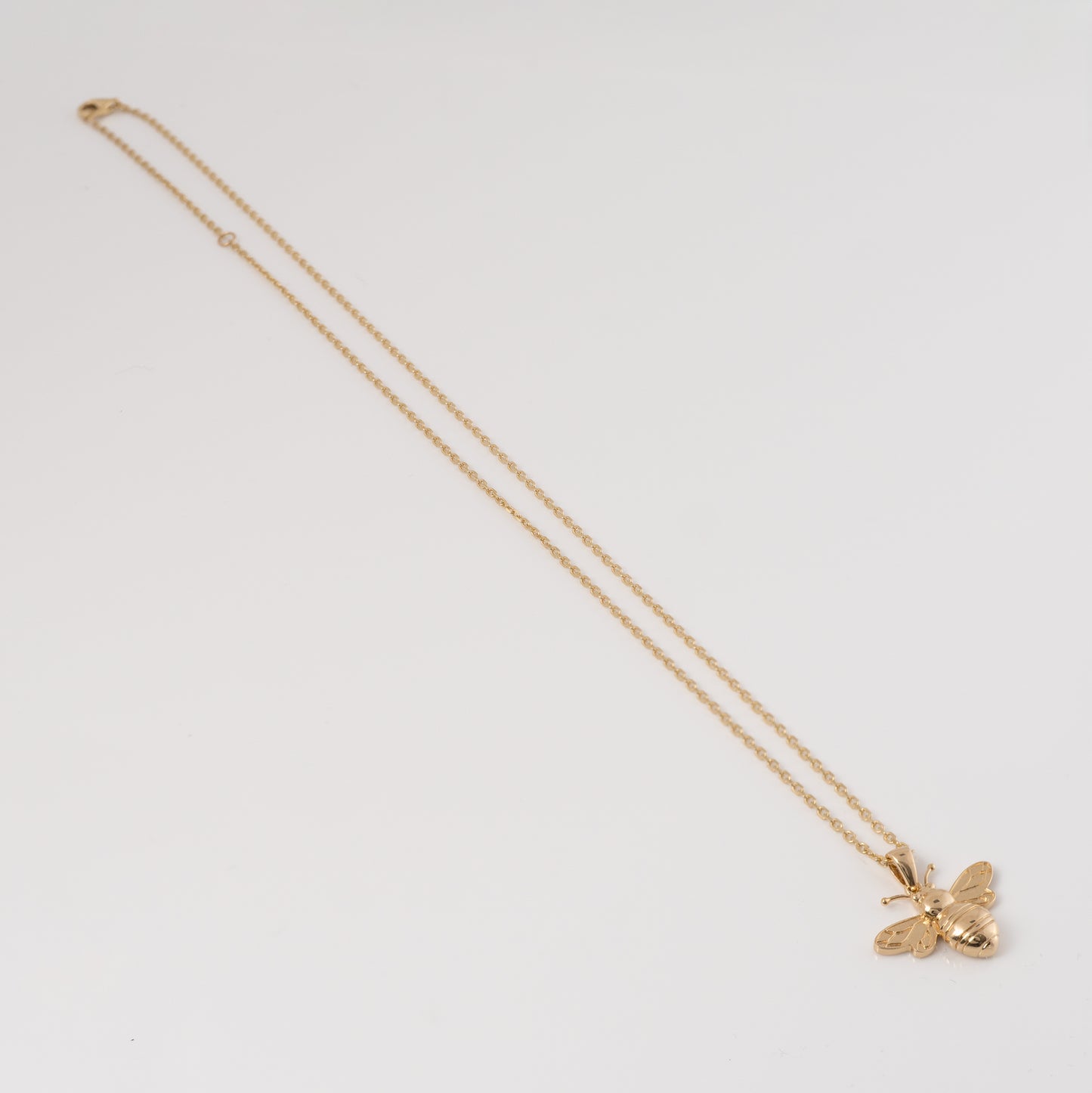Gold bee pendant necklace with adjustable chain stretched out, highlighting length and craftsmanship