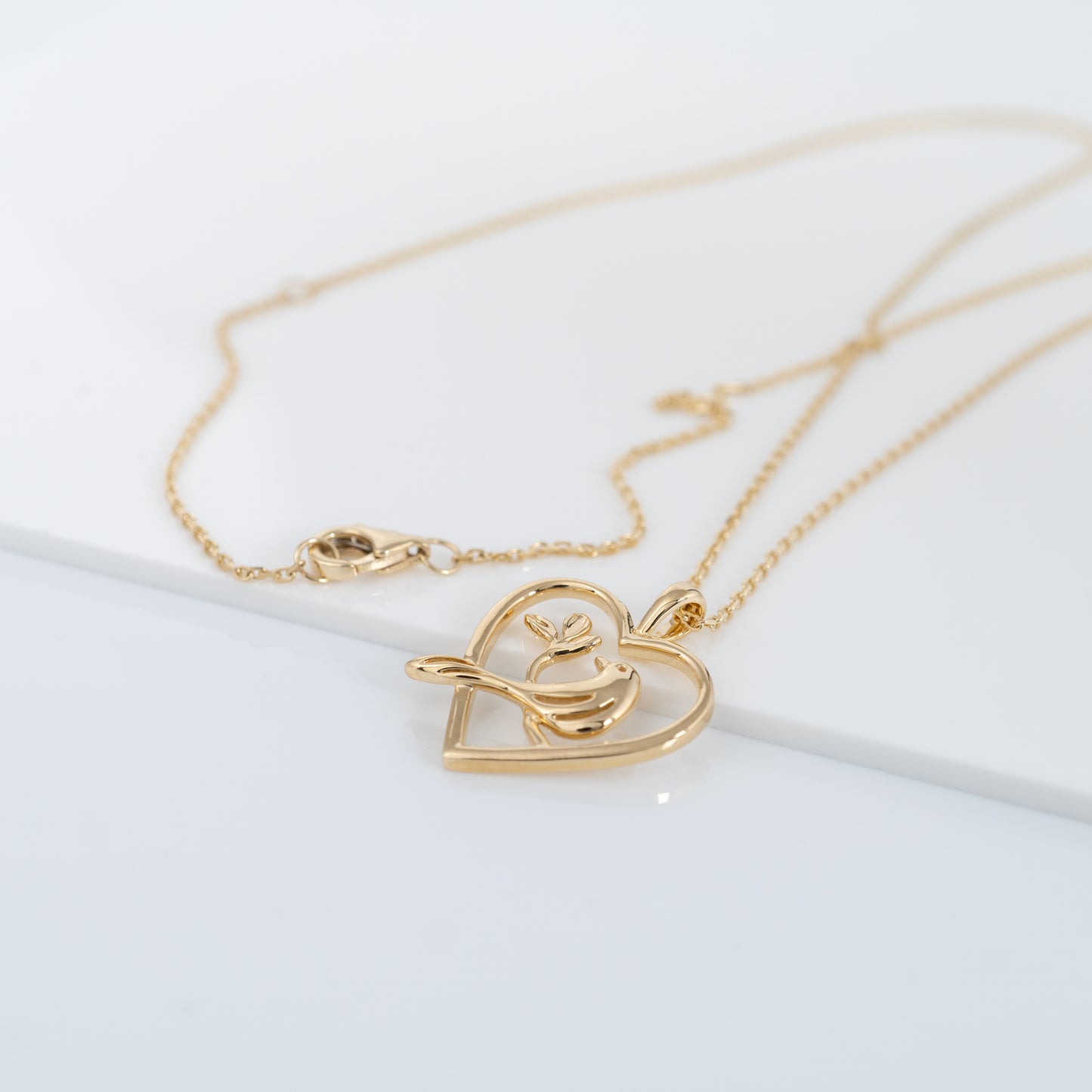 Flat lay of gold bird pendant with heart design