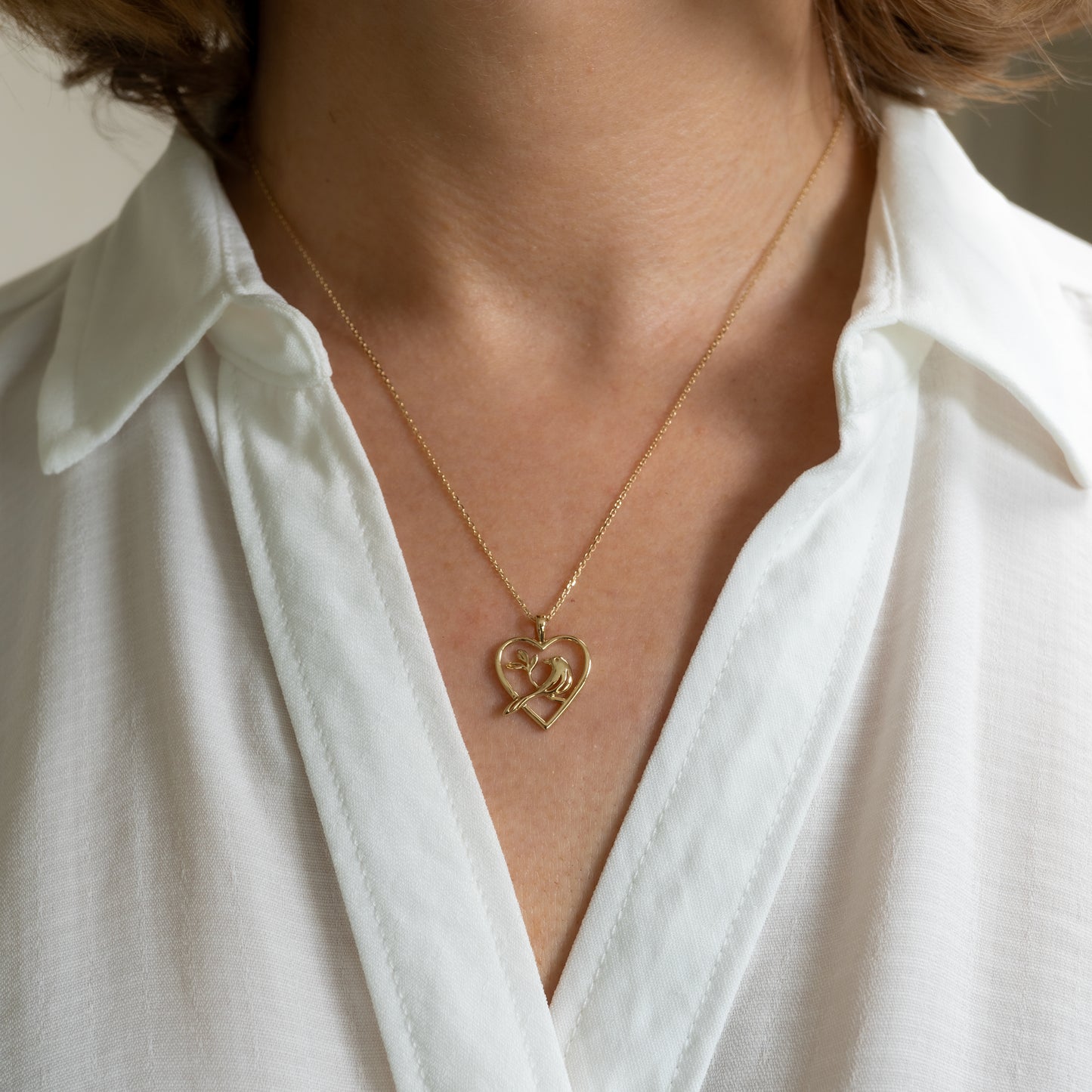 Gold bird pendant necklace worn on model