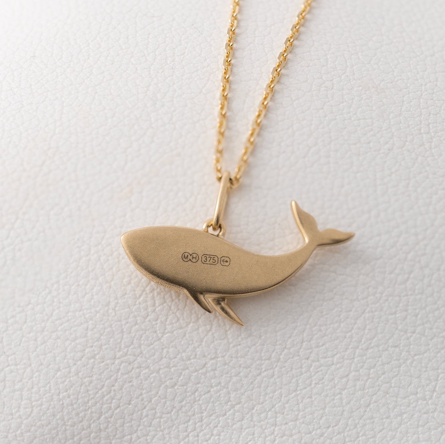 Reverse view of gold whale necklace showing British hallmarks