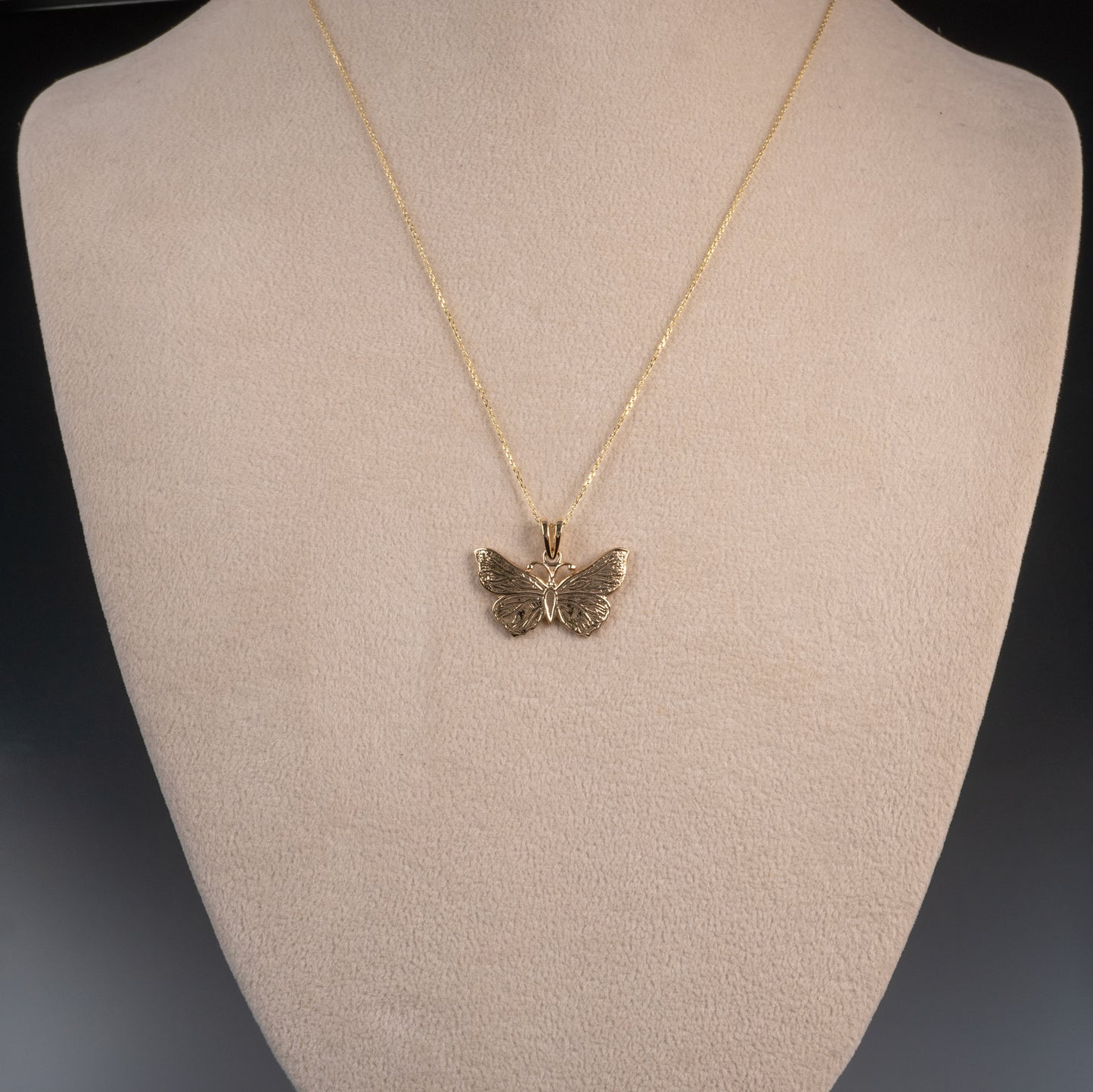 Gold butterfly necklace worn on mannequin bust – full view