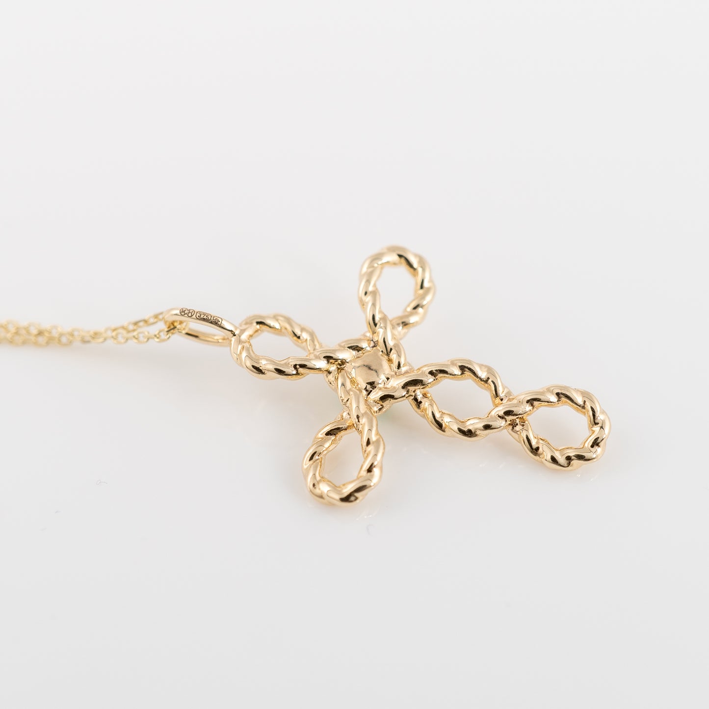 Back view of gold cross pendant with twisted rope design