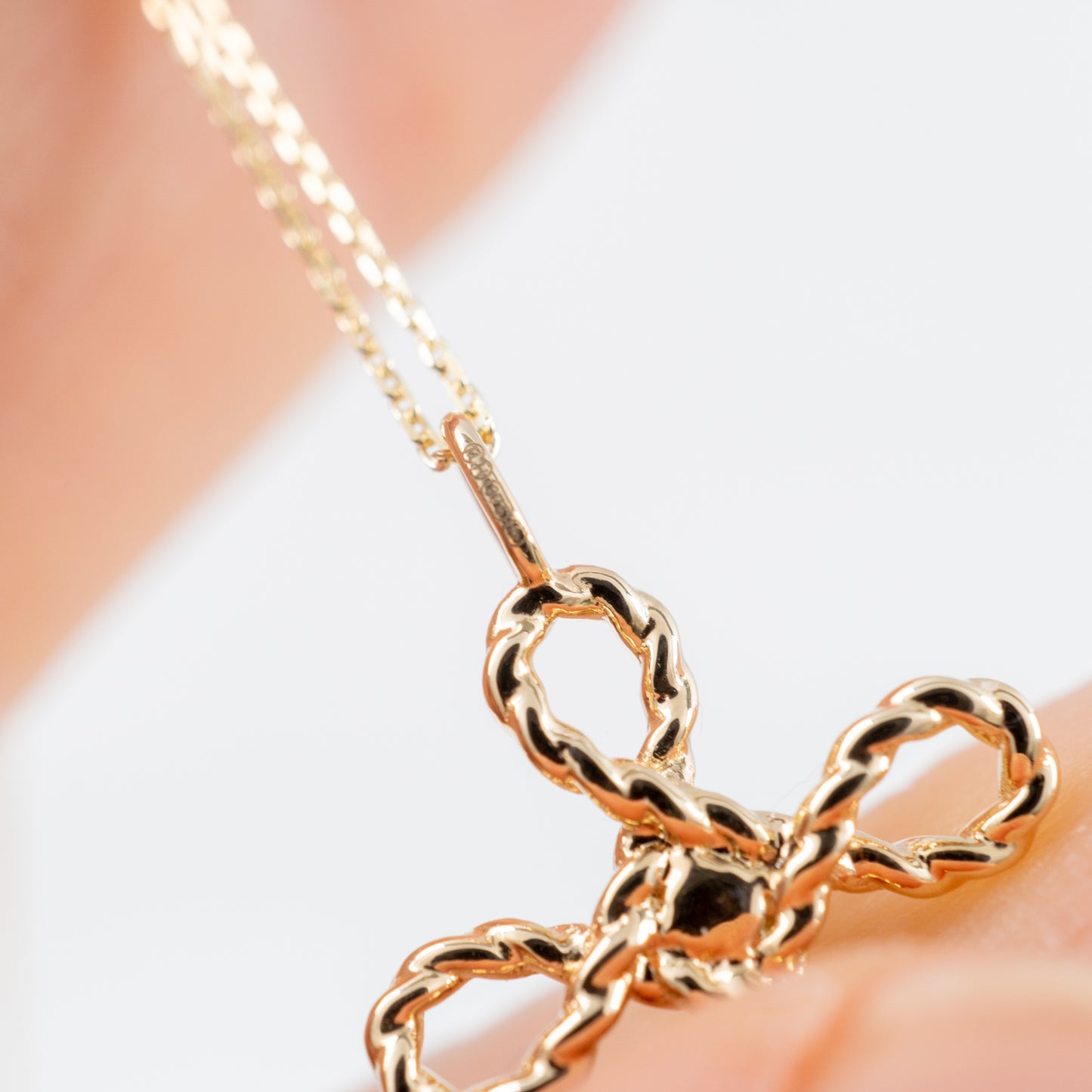 Gold cross necklace with green onyx – close-up shown in hand