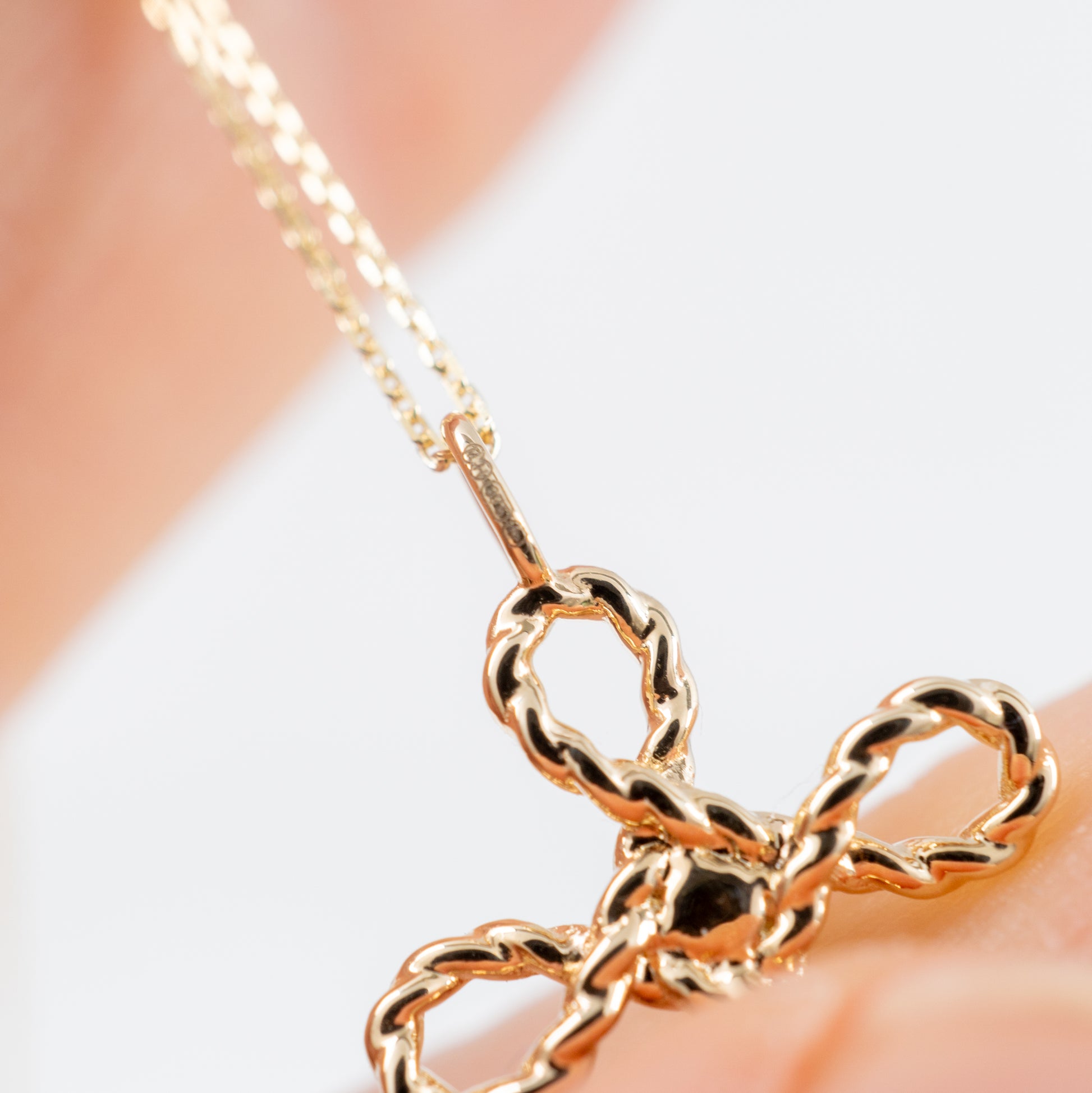 Gold cross necklace with green onyx – close-up shown in hand