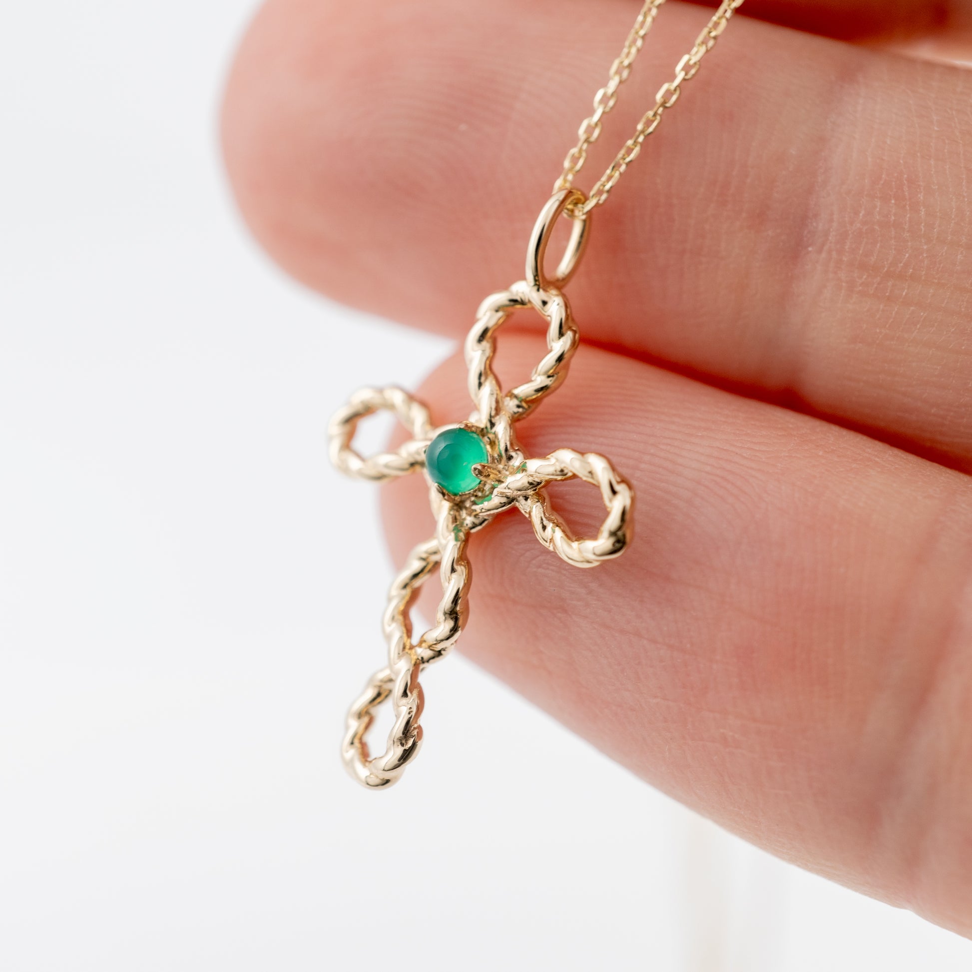 Gold cross necklace with green onyx – upright front view in hand