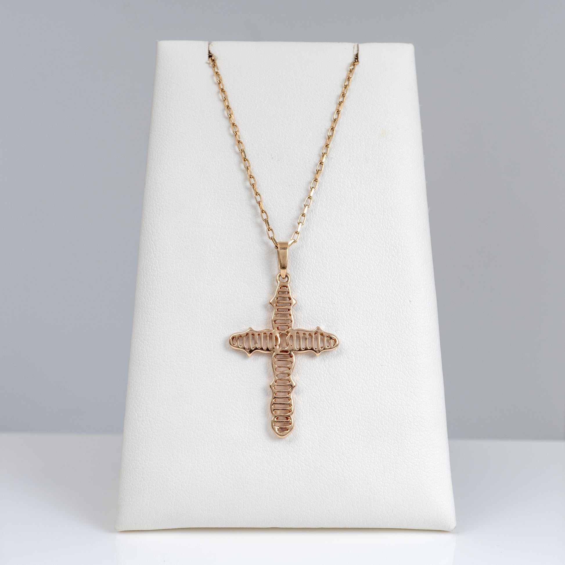 9ct gold crucifix necklace with cable chain displayed on jewellery stand