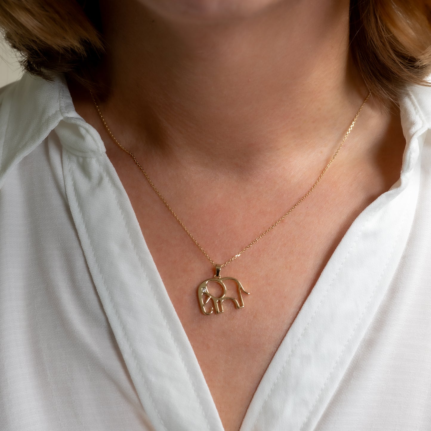 gold elephant necklace being worn neck white shirt
