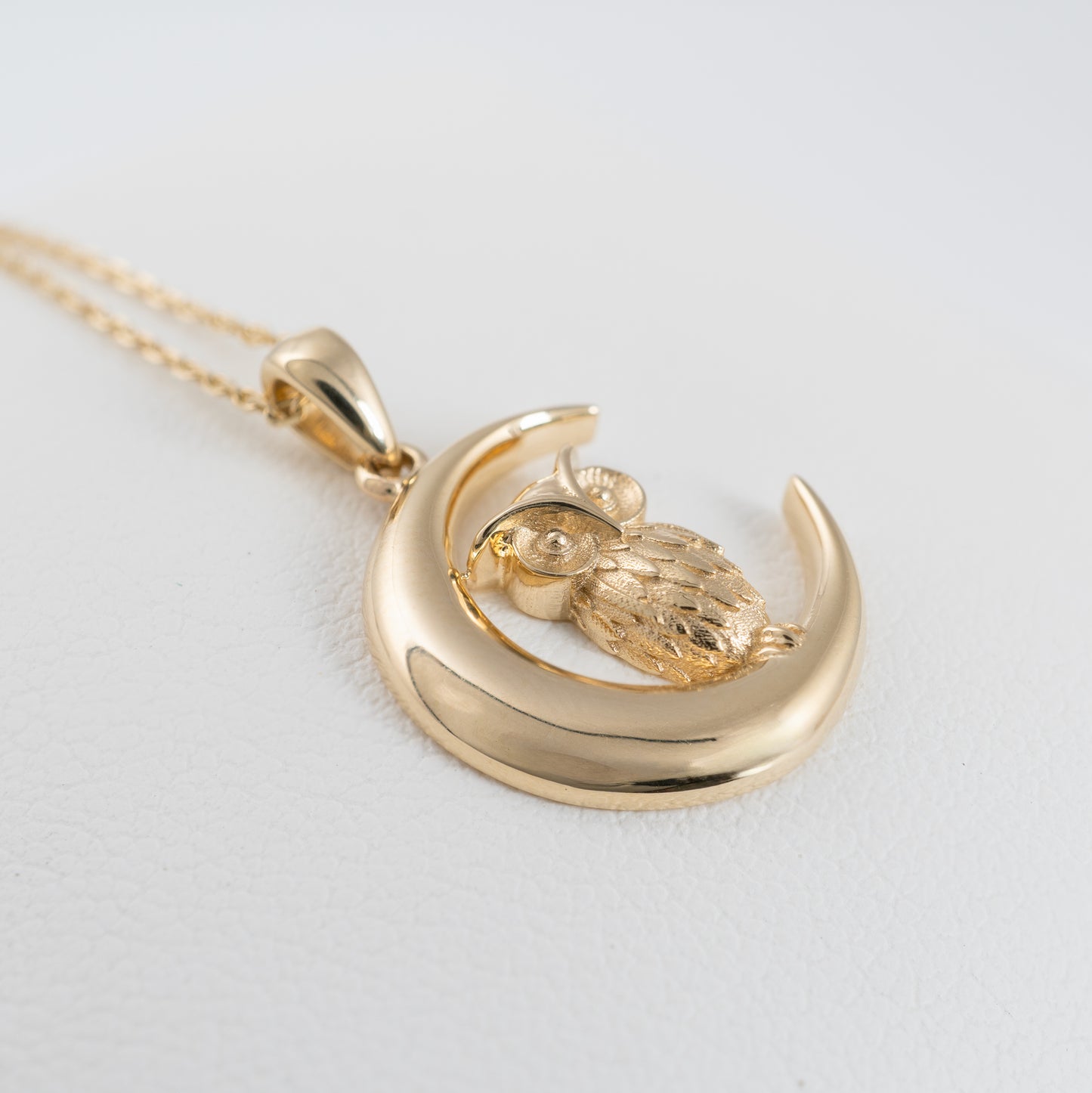 Close-up side of owl and crescent moon pendant in solid yellow gold