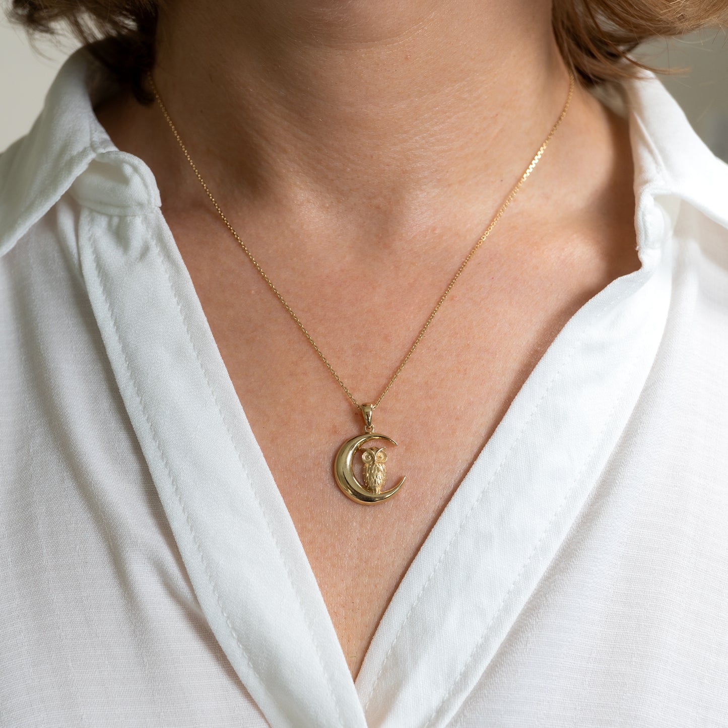 Model wearing gold owl pendant necklace on neckline