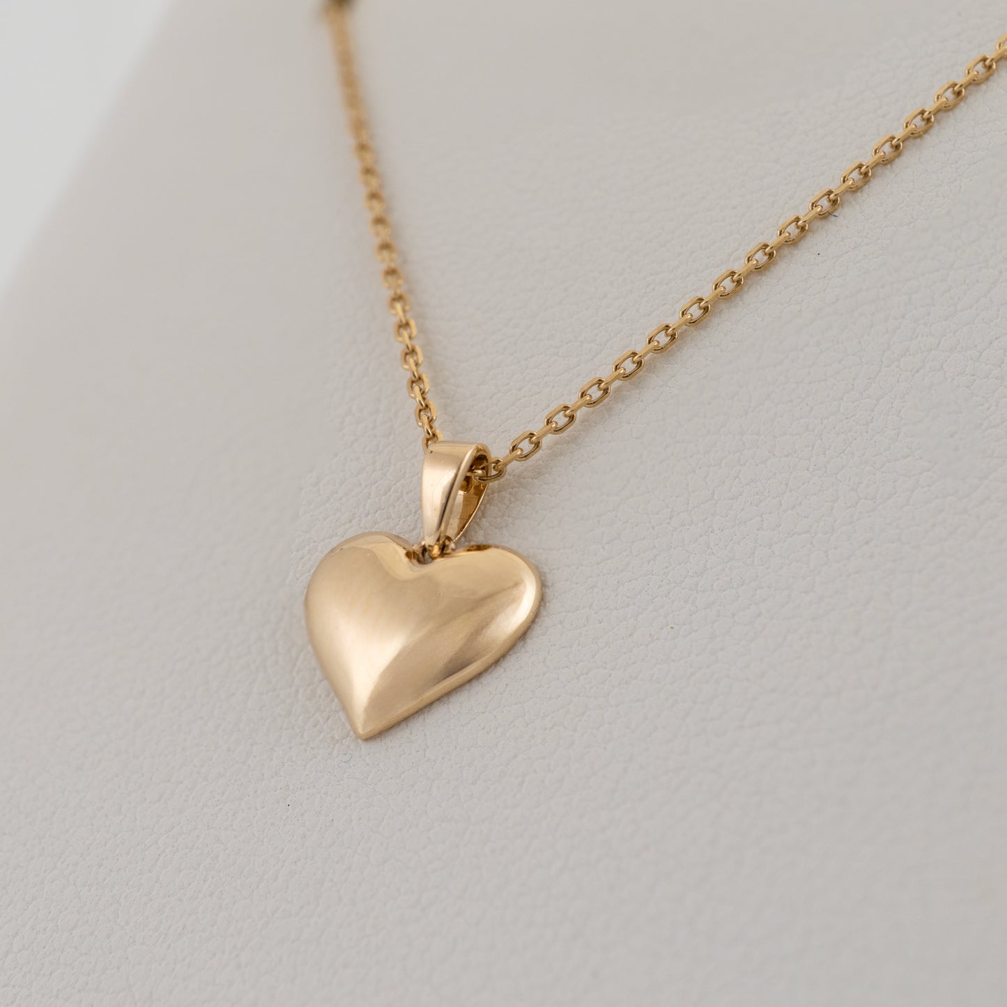 Close-up of puffed gold heart necklace with adjustable chain