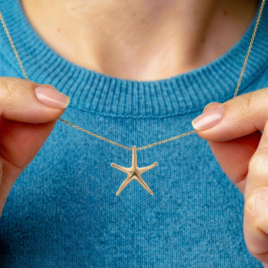 gold starfish necklace being worn by model wearing ocean blue colour jumper