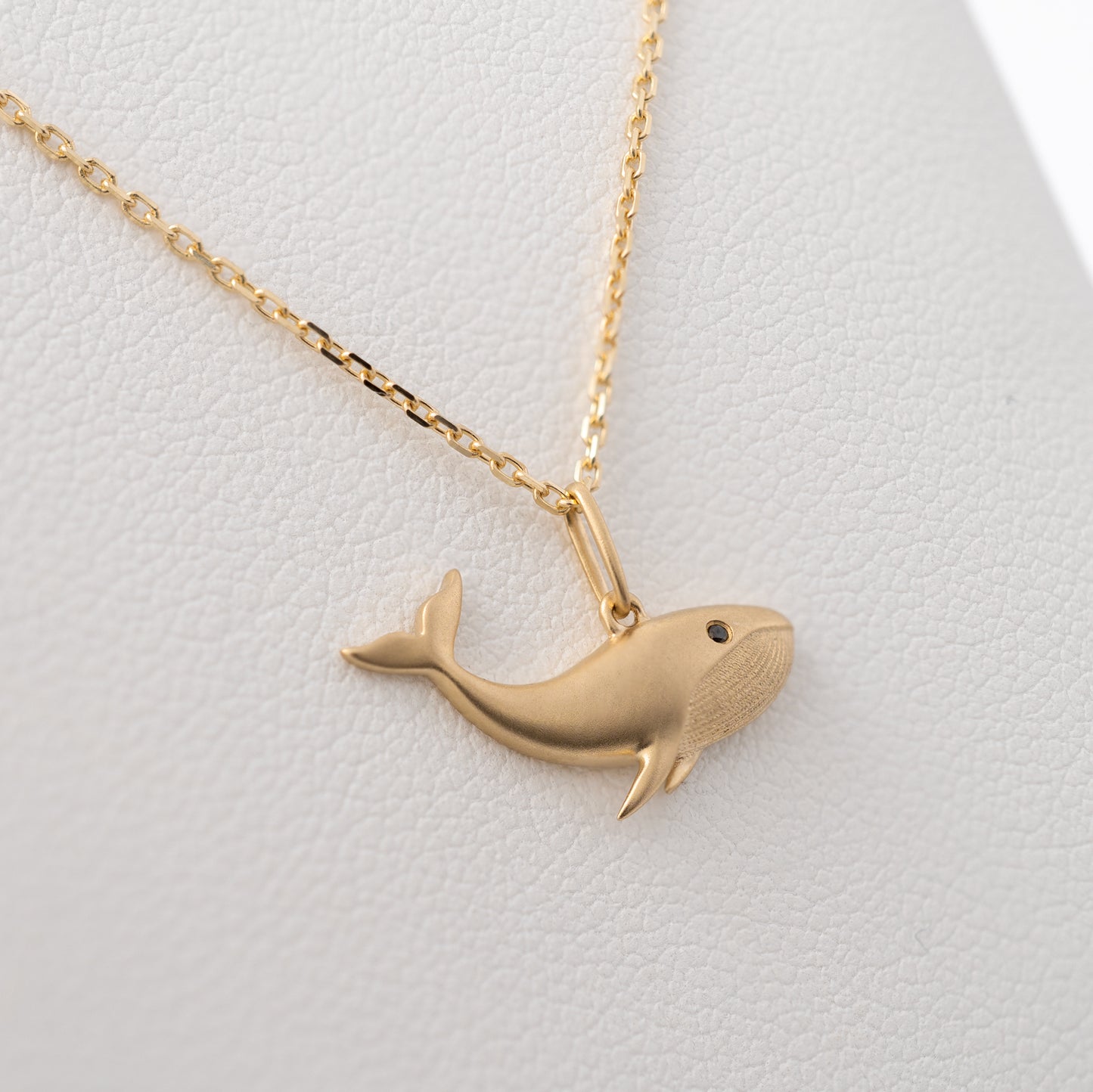 Side view of matte gold whale charm pendant