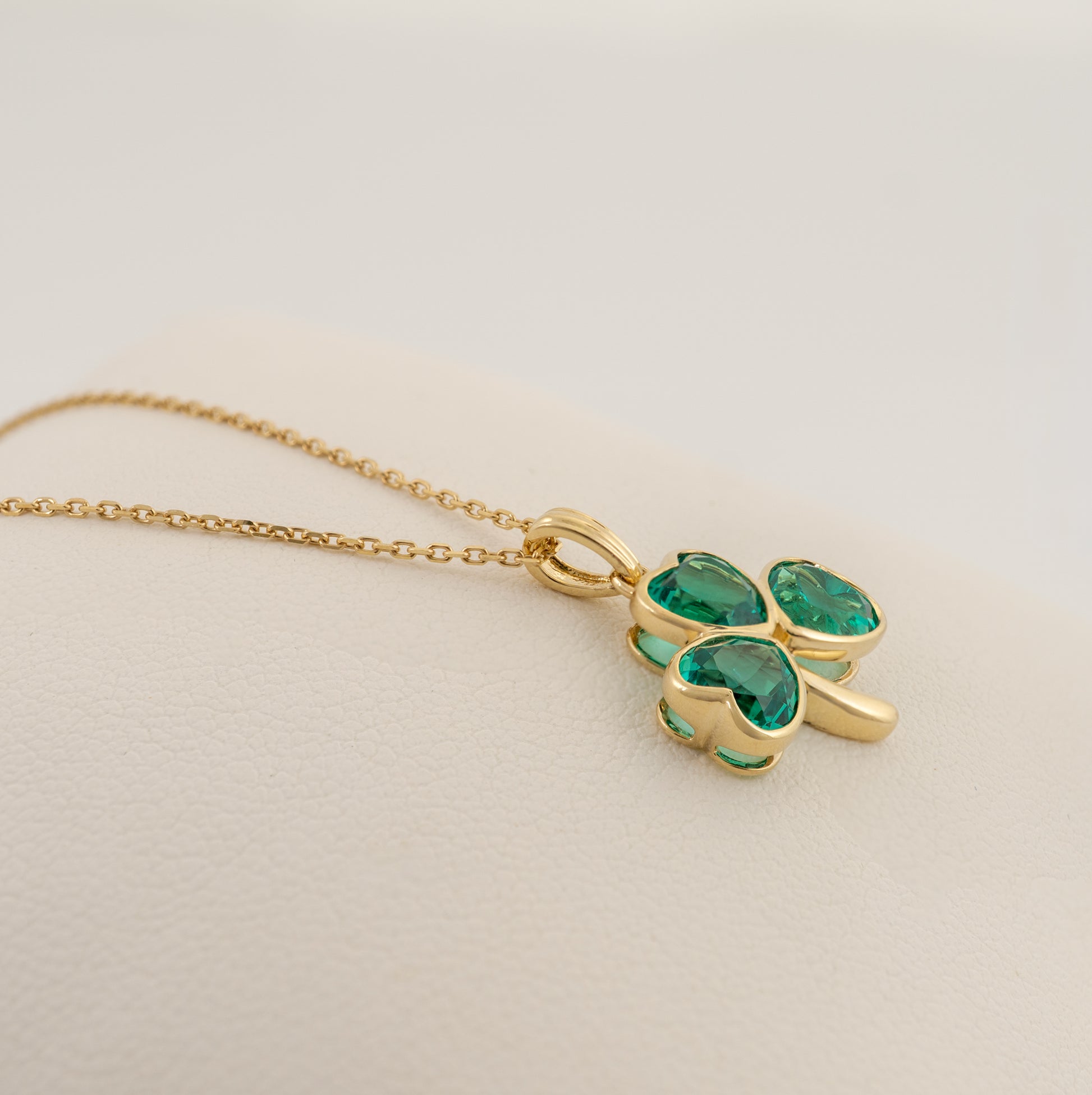 Lab emerald shamrock pendant laying flat on white background