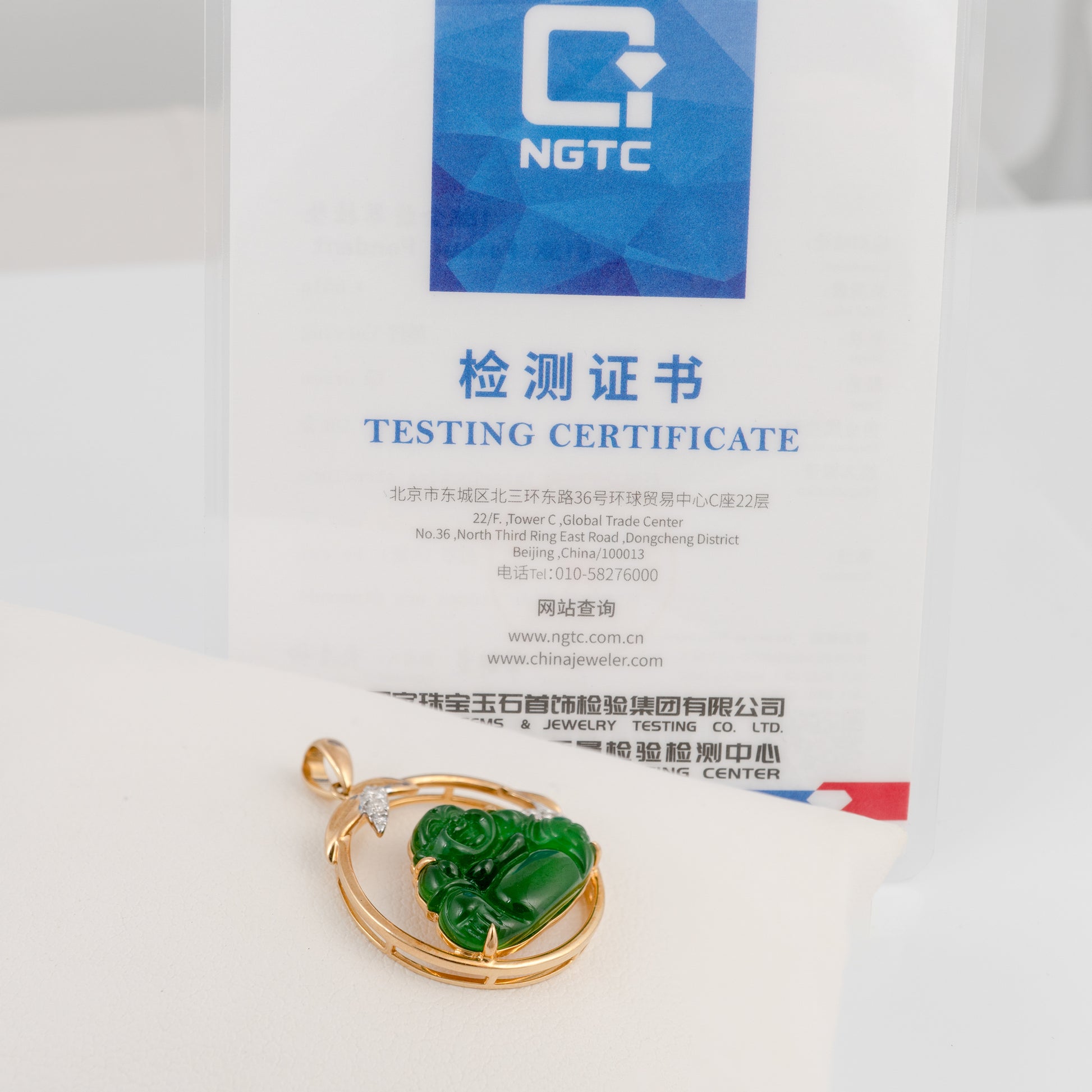 Green jade pendant with gold frame on a white background with NGTC testing certificate.