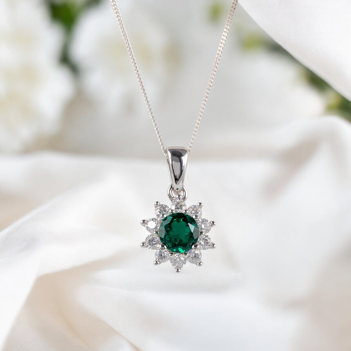 Lab grown emerald and moissanite halo pendant necklace – styled on satin cloth