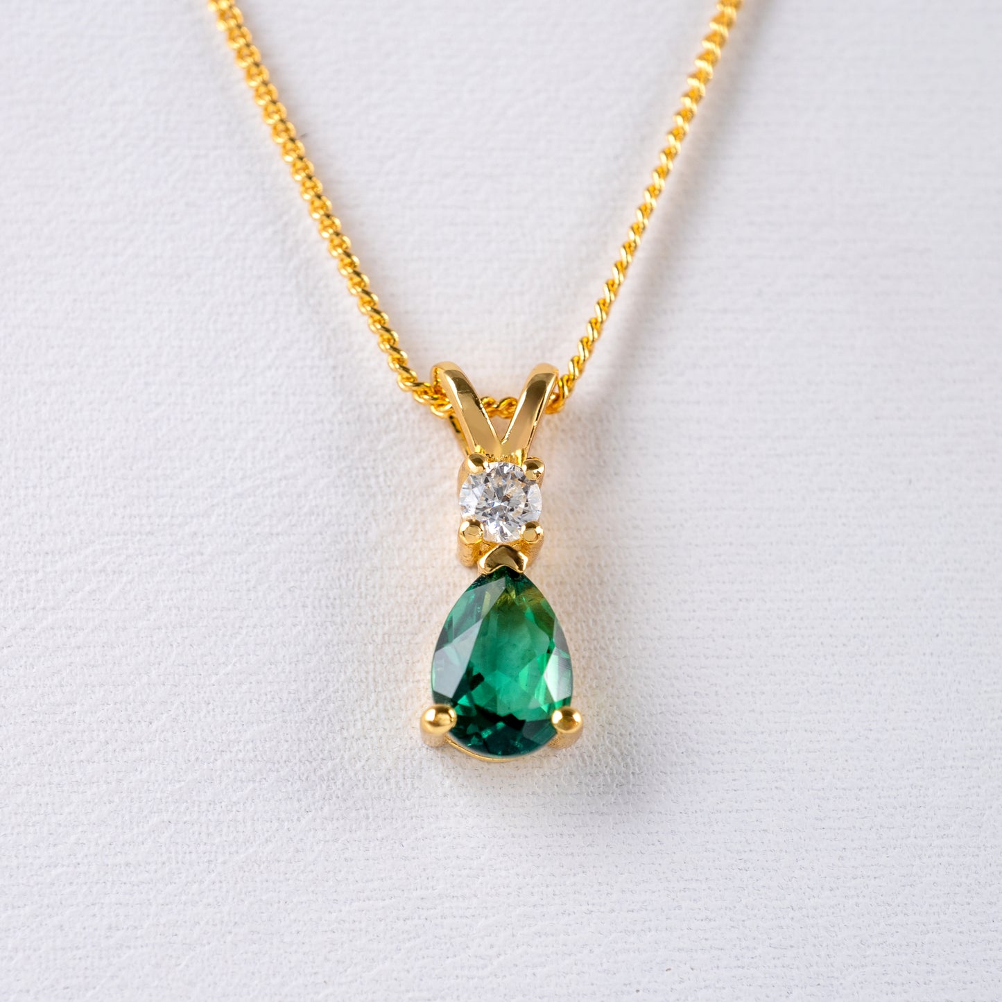 Close-up of lab emerald and moissanite pendant on gold vermeil chain