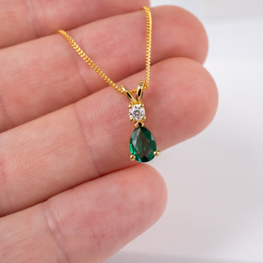 Lab emerald and moissanite pendant in gold vermeil held in hand