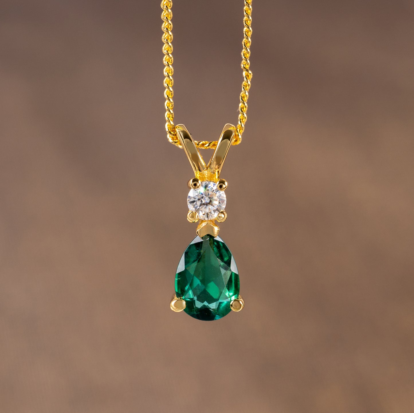 Lab emerald pendant necklace photographed against brown background